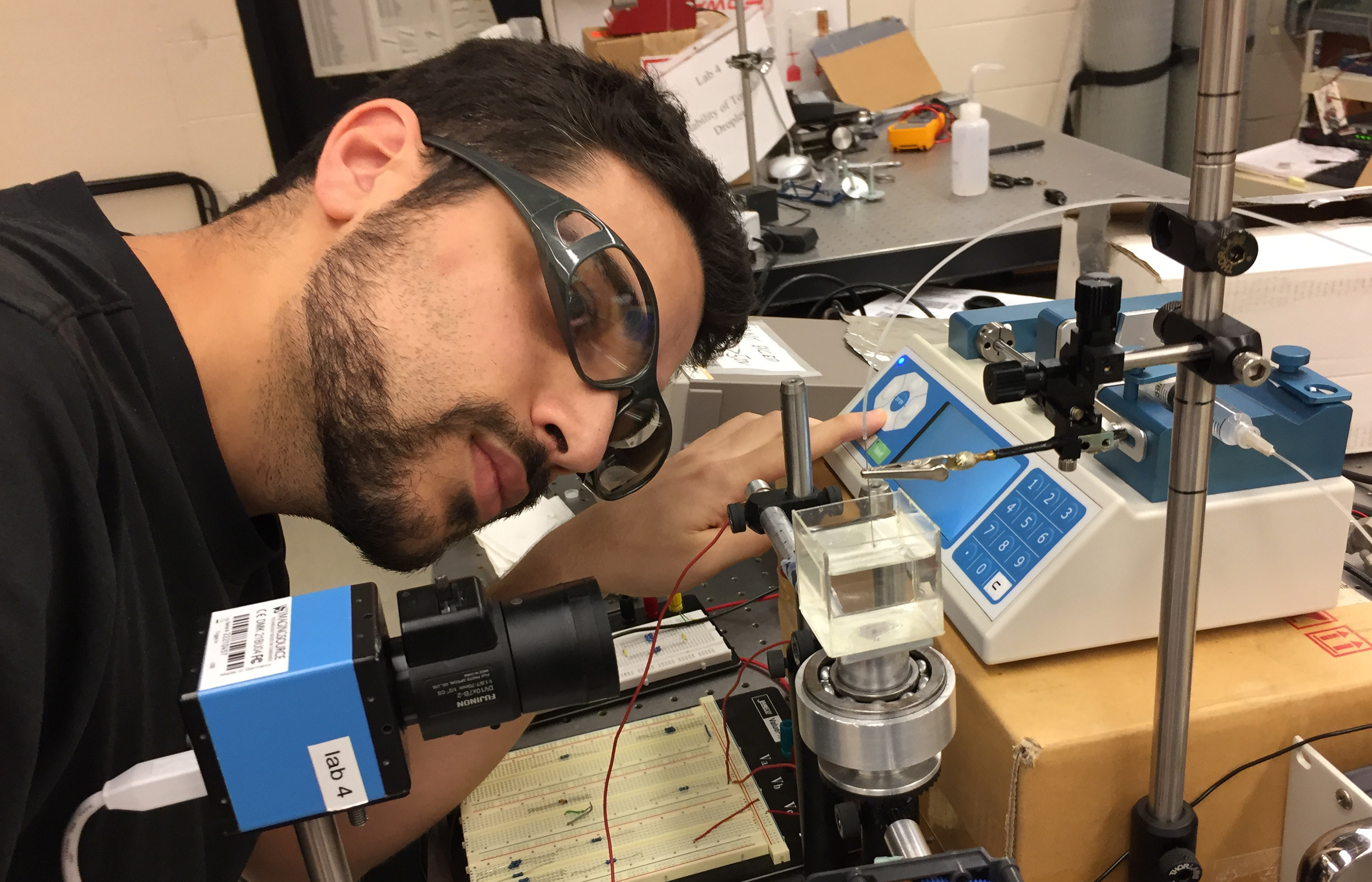 Georgia Tech Ph.D. candidate Alexandros Fragkopoulos adjusts equipment used to create unstable toroidal droplets in viscous silicone oil. The droplets are part of a study to understand how the droplets evolve into spherical forms. (Credit: John Toon, Georgia Tech)