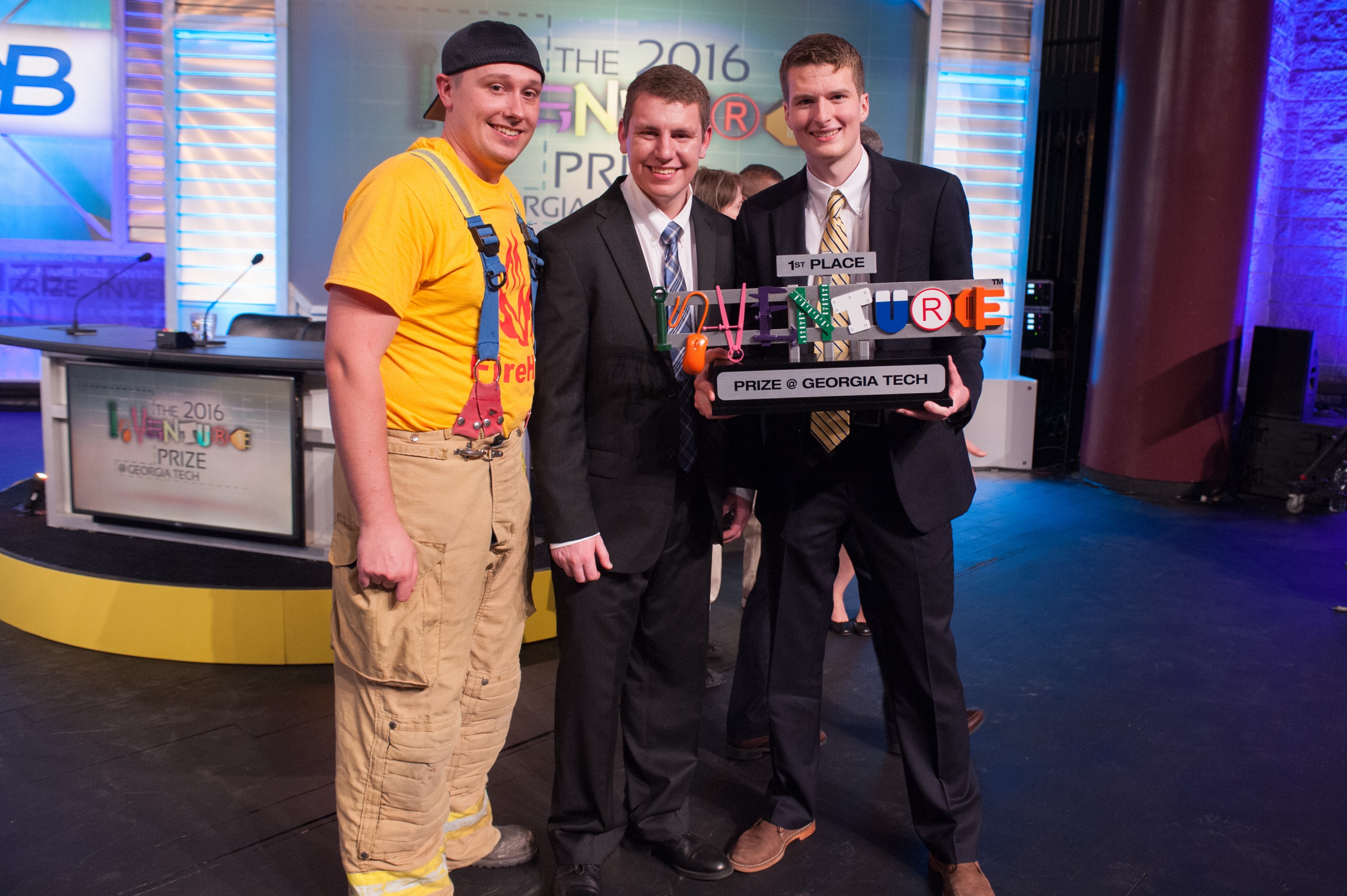 FireHUD, a device that helps firefighters track their vital signs while fighting fires, won the 2016 InVenture Prize at Georgia Tech.  The inventors – Zachary Braun, a computer engineering major, and Tyler Sisk, an electrical engineering major – will now represent Georgia Tech at the inaugural ACC InVenture Prize. The students are pictured with a firefighter who has used the device. Photo by Fitrah Hamid