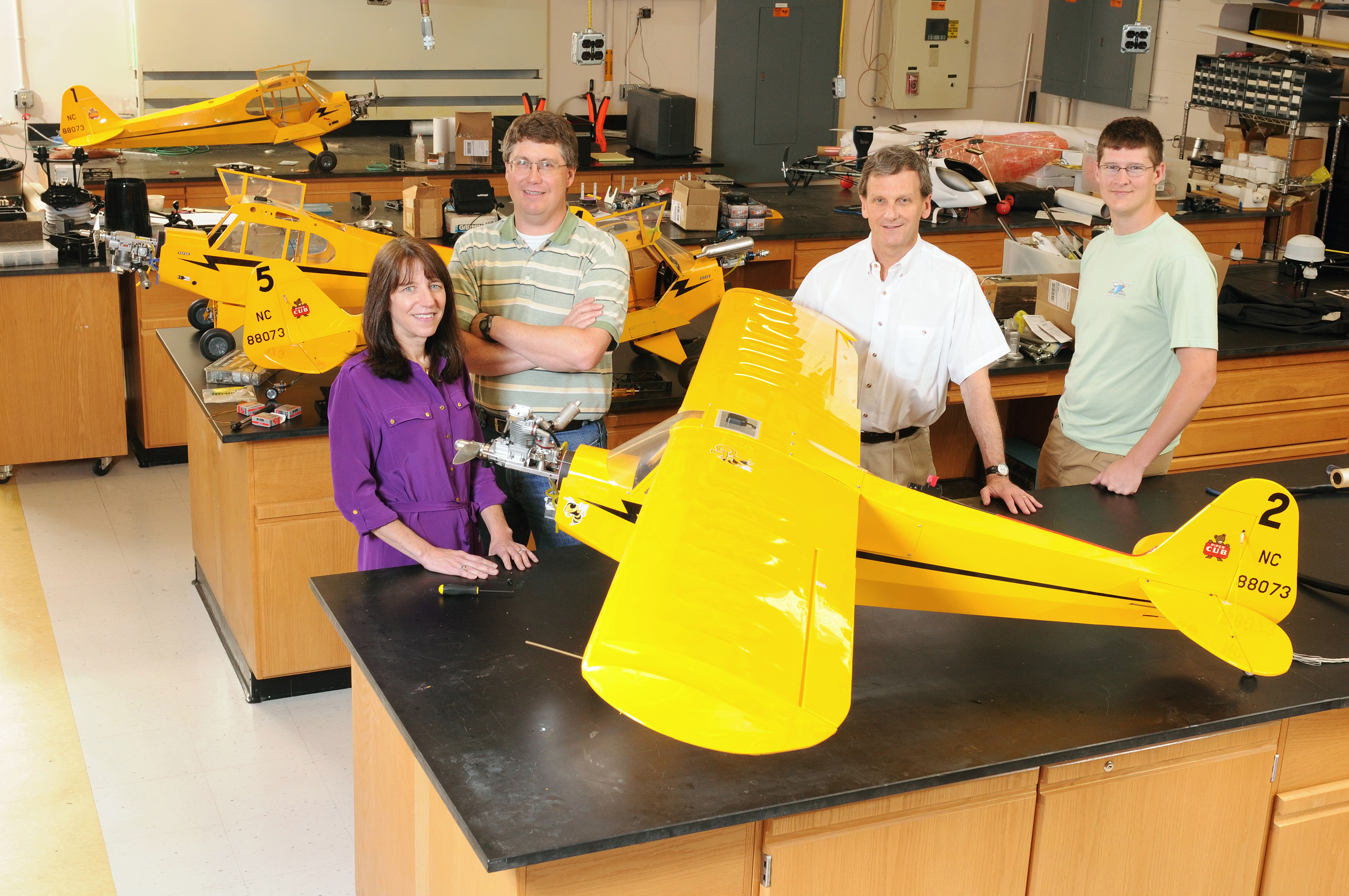 The Georgia Tech Research Institute (GTRI) uses quarter-scale Piper Cub aircraft for research on collaboration between unmanned aerial vehicles. Shown with the aircraft are (l-r) Lora Weiss, Gary Gray, Don Davis and Kyle Carnahan. (Photo: Gary Meek)