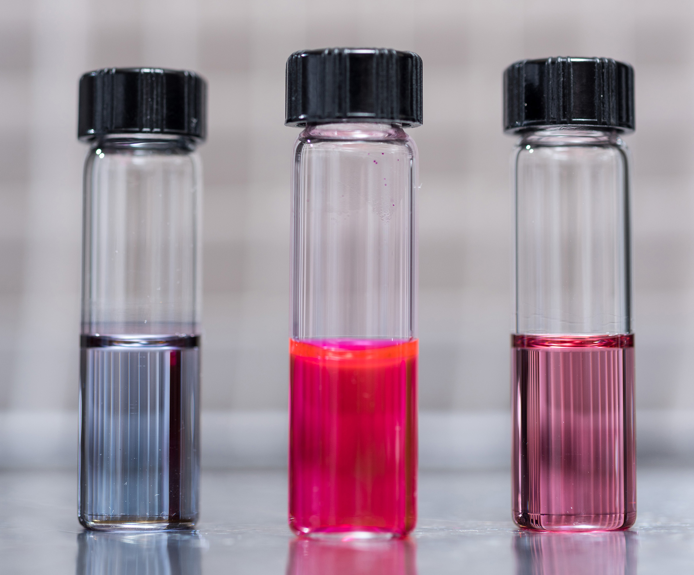 Image shows vials containing samples of hairy nanoparticles. The right and left images contain photo-responsive polymer-capped gold nanoparticles prior to and after self-assembly, respectively. The center vial shows dye released from self-assembled gold nanoparticles. The nanoparticles are made with light-sensitive materials that assemble and disassemble themselves when exposed to light of different wavelengths. (Credit: Rob Felt, Georgia Tech)