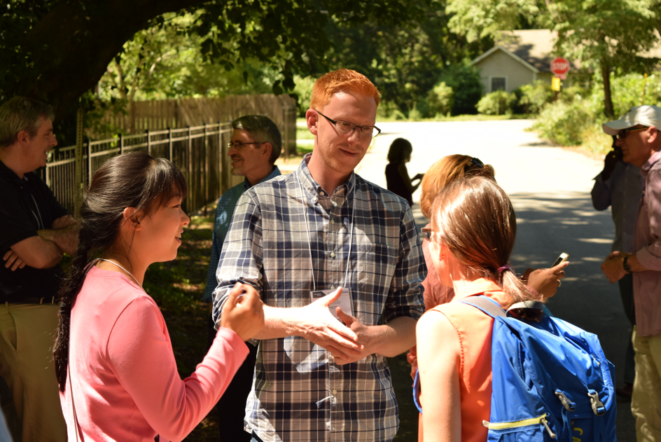 James Field (center), a graduate student working with the Center for Serve-Learn-Sustain, talks with conference attendees during the tour of the Emerald Corridor. Attendees had the chance to discuss issues related to climate, food, water, energy, and community development. 
