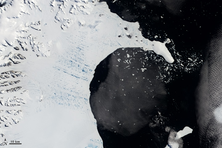 Before its sudden shattering, numerous meltwater ponds riddled Antarctic ice shelf Larsen B. They are seen in this 2002 satellite image as a matrix of aquamarine spots. Scientists believe that the ponds hydrofractured the kilometer-thick ice shelf, causing its swift destruction. Credit: NASA Earth Observatory