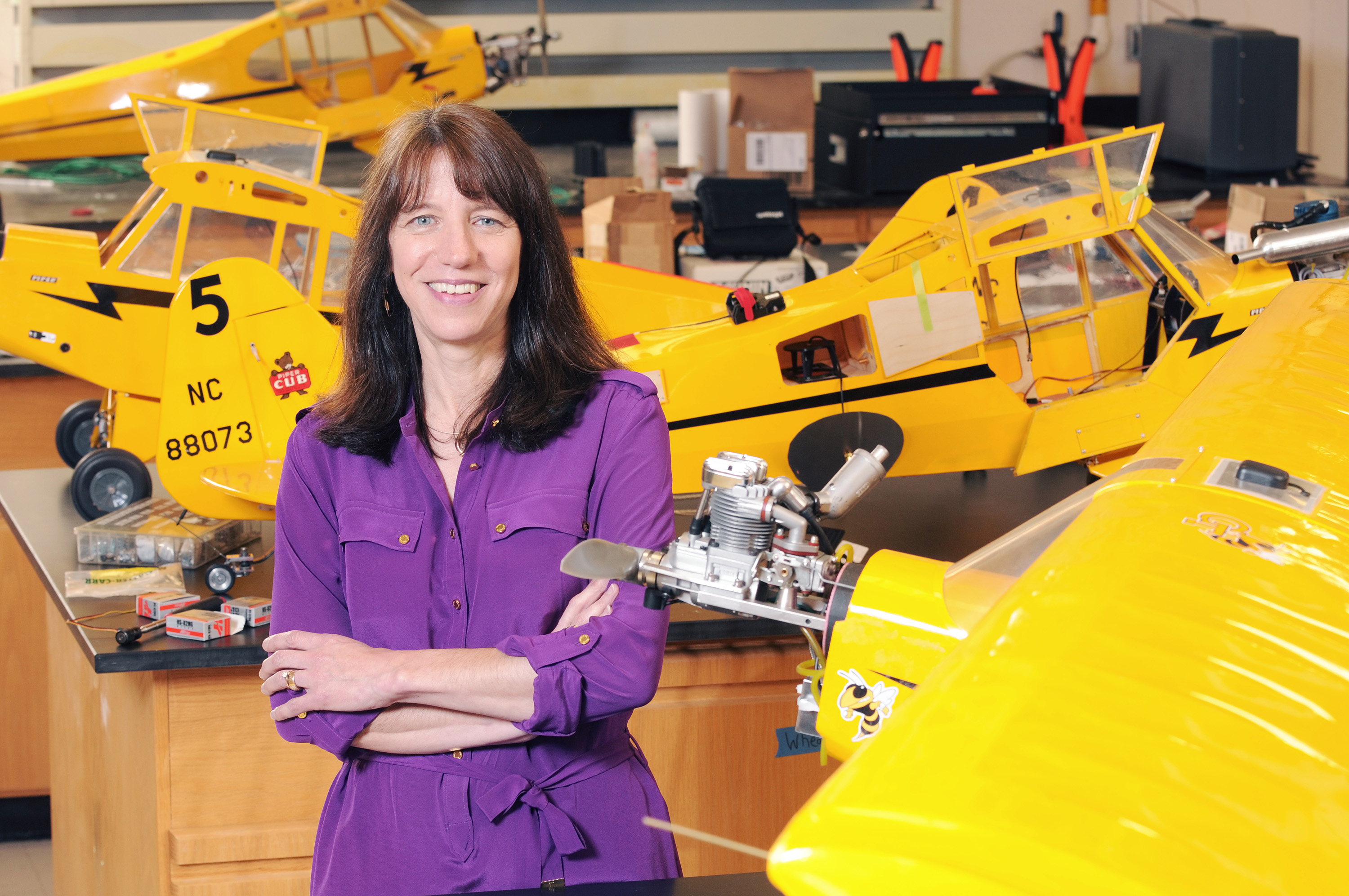 Lora Weiss, chief scientist in the Georgia Tech Research Institute (GTRI), is shown with quarter-scale Piper Cub aircraft used in research on collaboration between unmanned aerial vehicles. (Photo: Gary Meek)