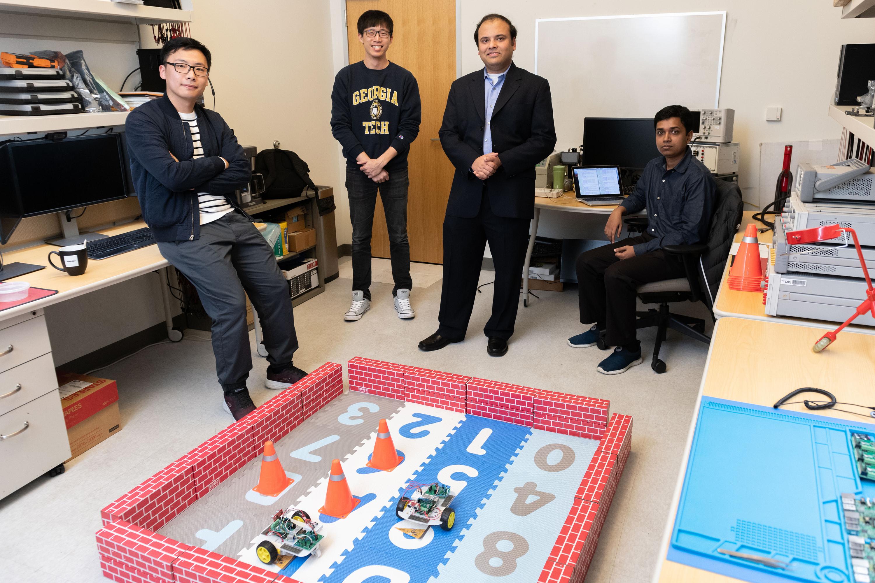 Georgia Tech Researchers Ningyuan Cao, Muya Chang, Arijit Raychowdhury and Anupam Golder with a laboratory demonstration of an ultra-low power hybrid chip driving two small robotic cars. (Photo: Allison Carter, Georgia Tech)