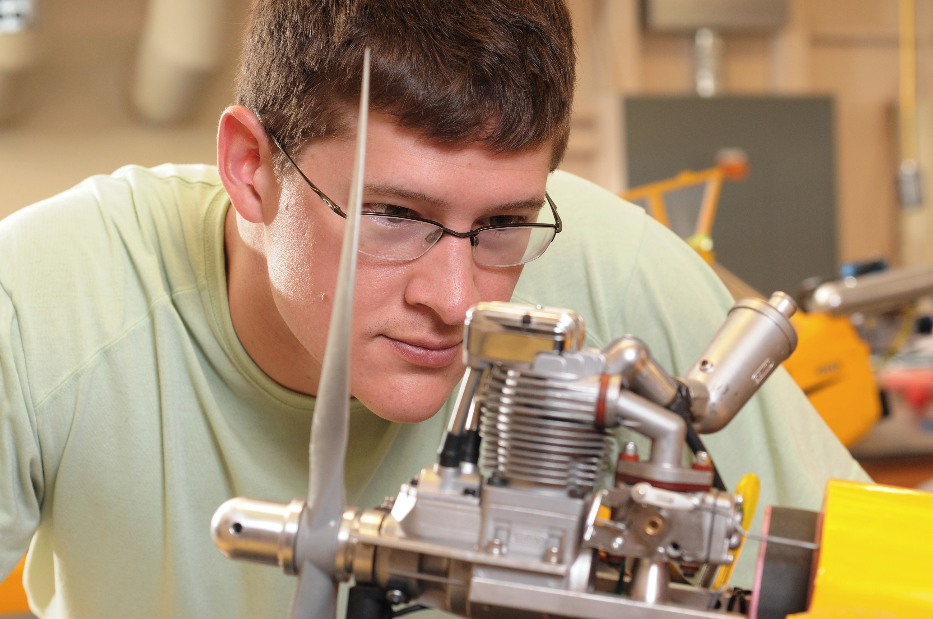 Kyle Carnahan, a researcher in the Georgia Tech Research Institute (GTRI), adjusts the engine of a quarter-scale Piper Cub aircraft used for research into collaboration between unmanned aerial vehicles. (Photo: Gary Meek)