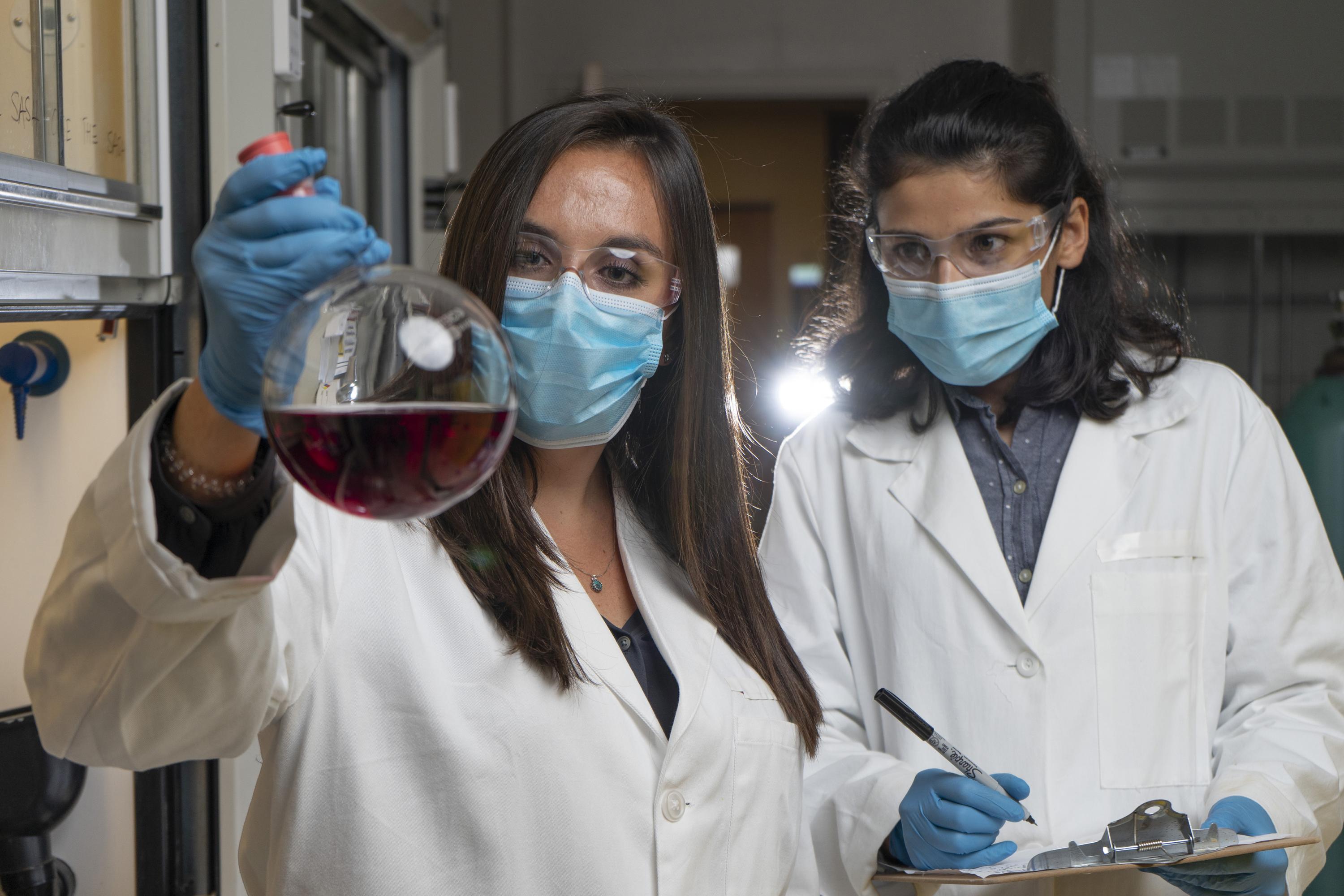 Georgia Tech graduate research assistants Kirstie Thompson and Ronita Mathias with a flask containing polymer materials used to create a new membrane technology that could reduce carbon emissions and energy intensity associated with refining crude oil. (Credit: Christopher Moore, Georgia Tech)