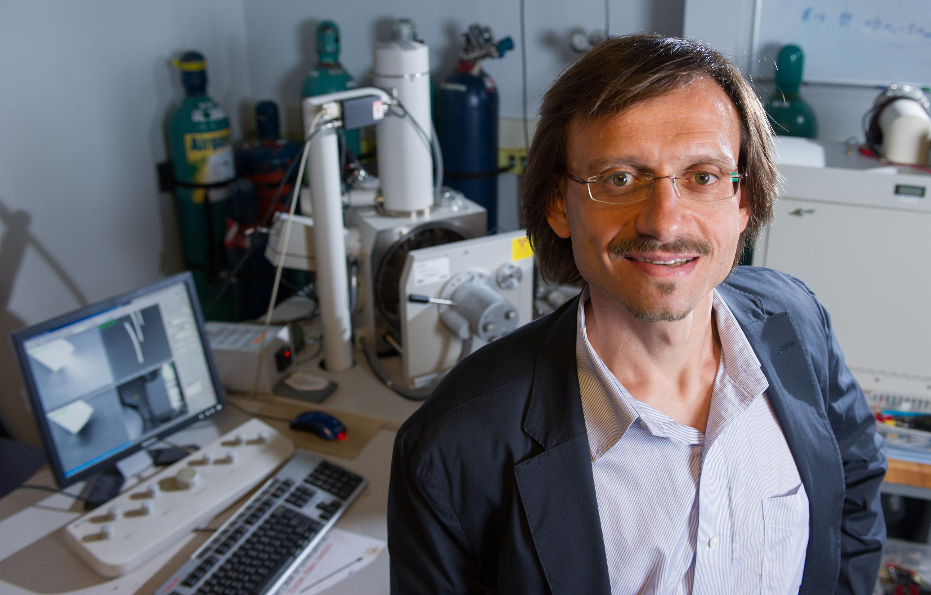 Photograph shows professor Andrei Fedorov with the FEBID system developed at Georgia Tech. The screen images show the high aspect ratio nanopillar depositions produced using energetic gas-jet assisted electron beam deposition. (Georgia Tech Photo: Rob Felt)