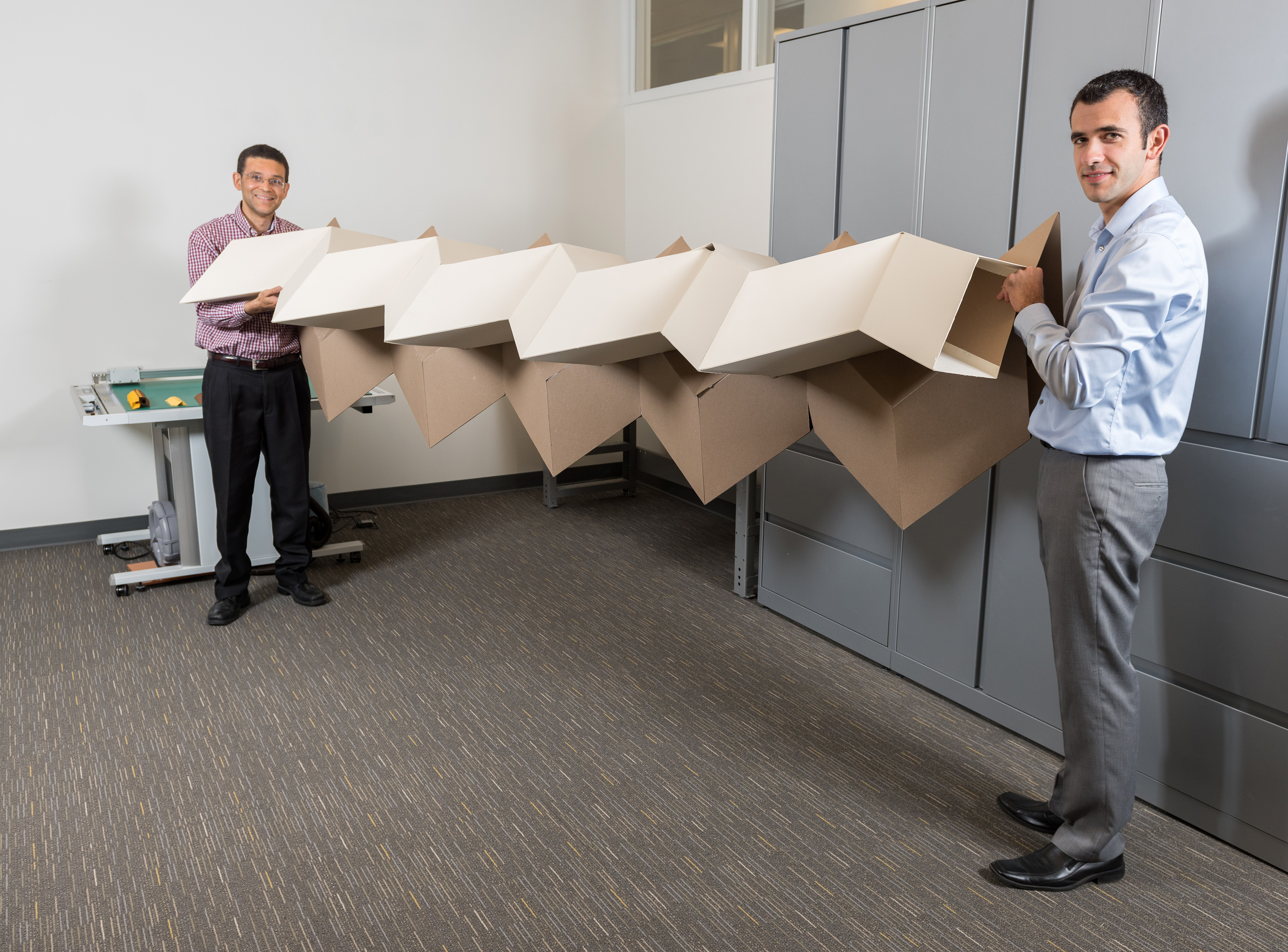 Researchers Glaucio Paulino (left) and Evgueni Filipov show a large origami structure that can be folded into a much smaller space. Filipov is from University of Illinois at Urbana-Champaign; Paulino is from the Georgia Institute of Technology. (Credit: Rob Felt, Georgia Tech)