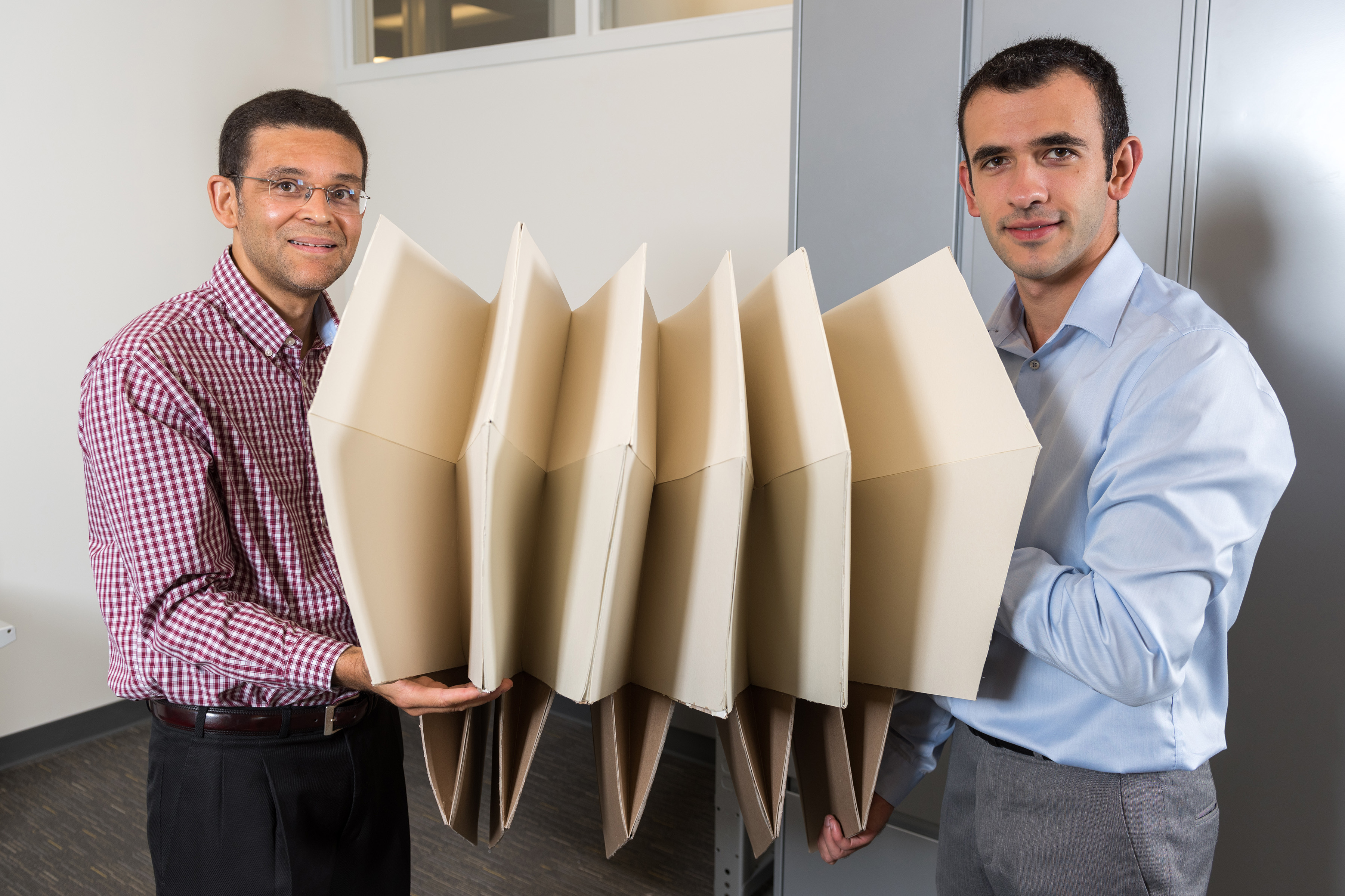 Researchers Glaucio Paulino (left) and Evgueni Filipov show the same large origami structure that has been folded to a much smaller space. Filipov is from University of Illinois at Urbana-Champaign; Paulino is from the Georgia Institute of Technology. (Credit: Rob Felt, Georgia Tech)