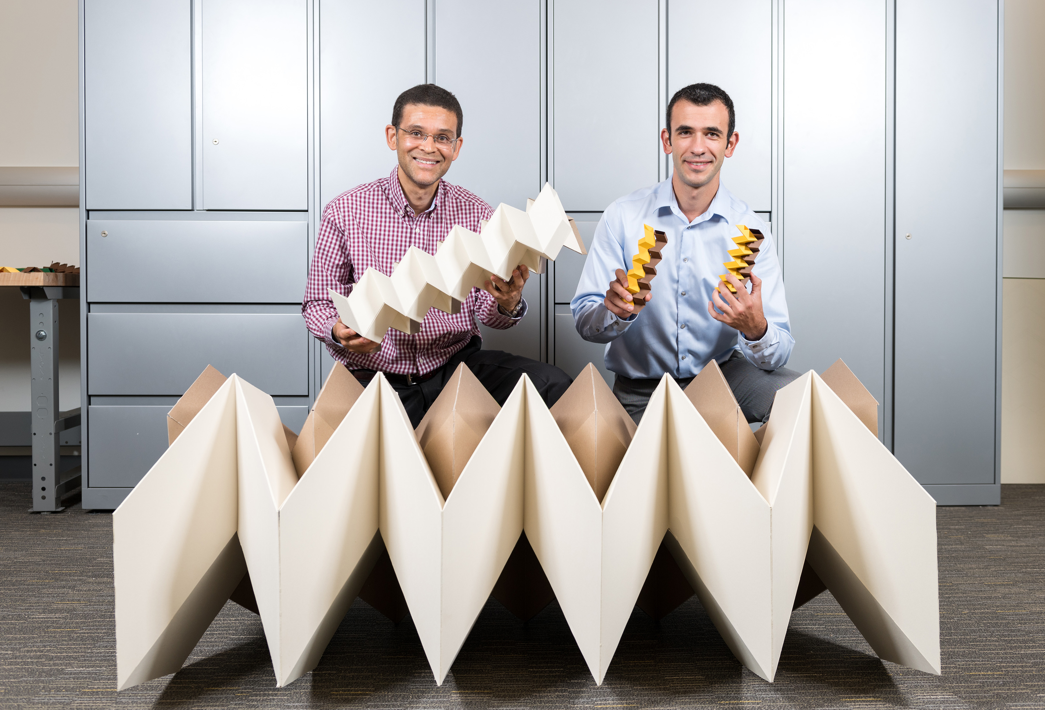 Researchers Glaucio Paulino (left) and Evgueni Filipov with three origami structures showing the size flexibility of the "zippered tube" system. Filipov is from University of Illinois at Urbana-Champaign; Paulino is from the Georgia Institute of Technology. (Credit: Rob Felt, Georgia Tech) 