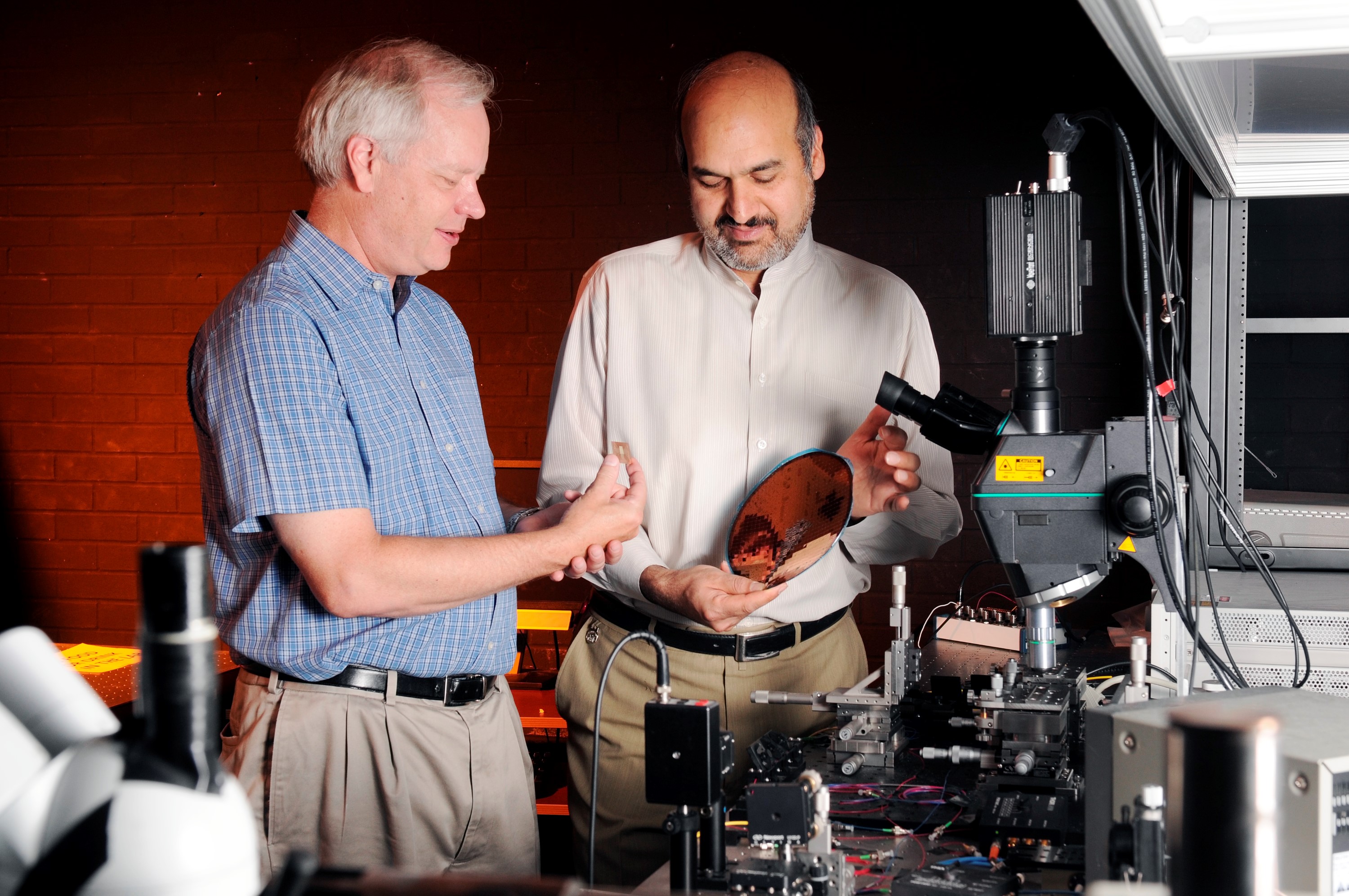 Professor Ken Sandhage, left, and Professor Ali Adibi examine a sensing device and a silicon wafer in a laboratory at Georgia Tech. (Credit: Gary Meek)