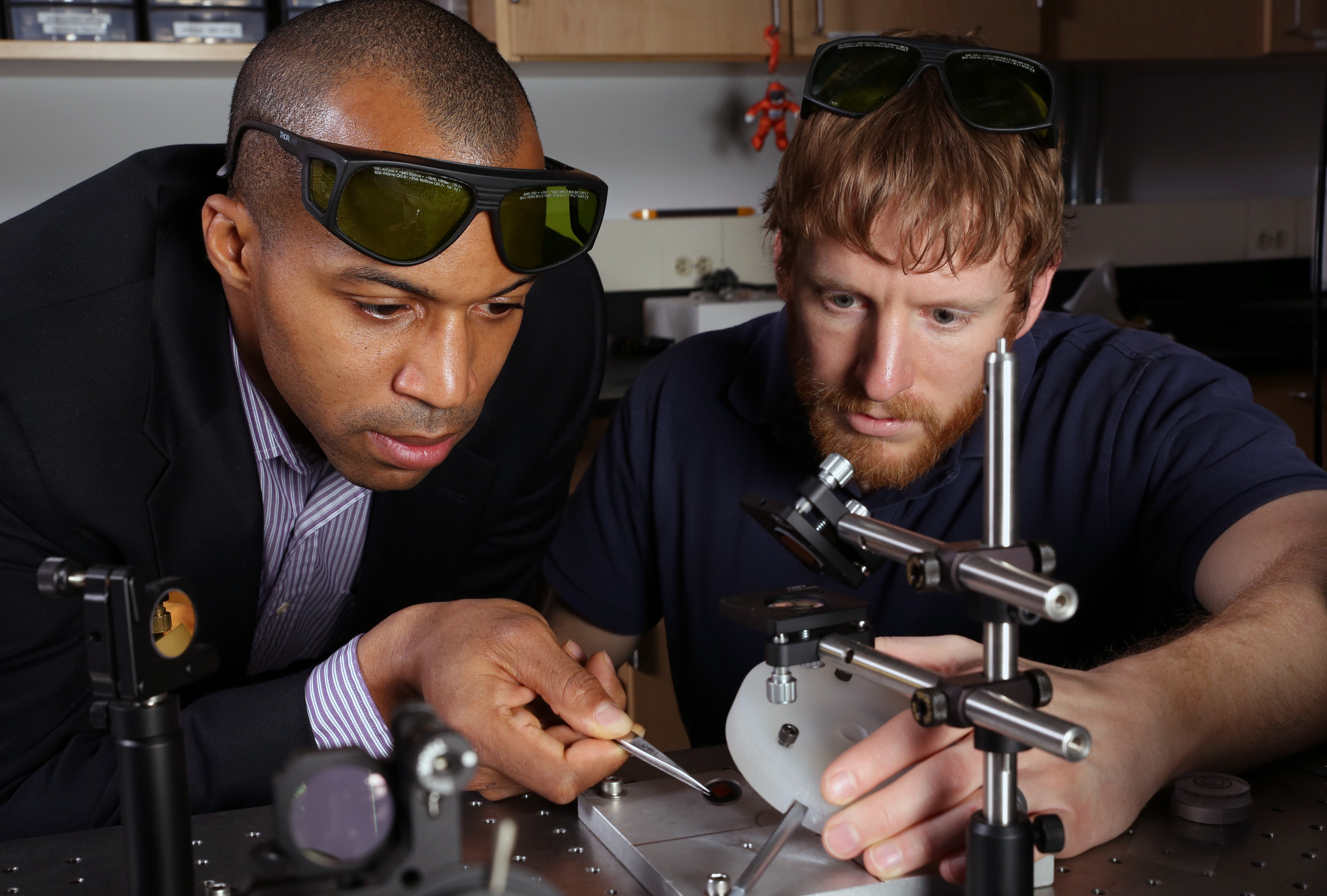 Assistant professor Baratunde Cola, from the George W. Woodruff School of Mechanical Engineering at Georgia Tech, and Ph.D. student Tom Bougher, show photoacoustic test equipment used to measure heat conductance of a new polymer material developed for thermal management. (Georgia Tech Photo: Candler Hobbs)