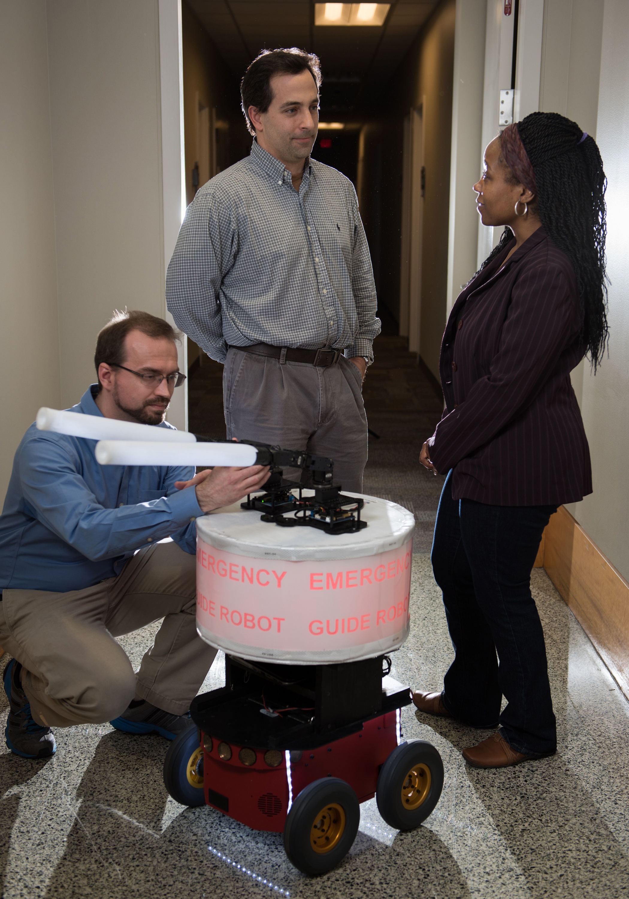GTRI Research Engineer Paul Robinette adjusts the “arms” on the “Rescue Robot,” while (L-R) GTRI Senior Research Engineer Alan Wagner and School of Electrical and Computer Engineering Professor Ayanna Howard look on. (Credit: Rob Felt, Georgia Tech)
