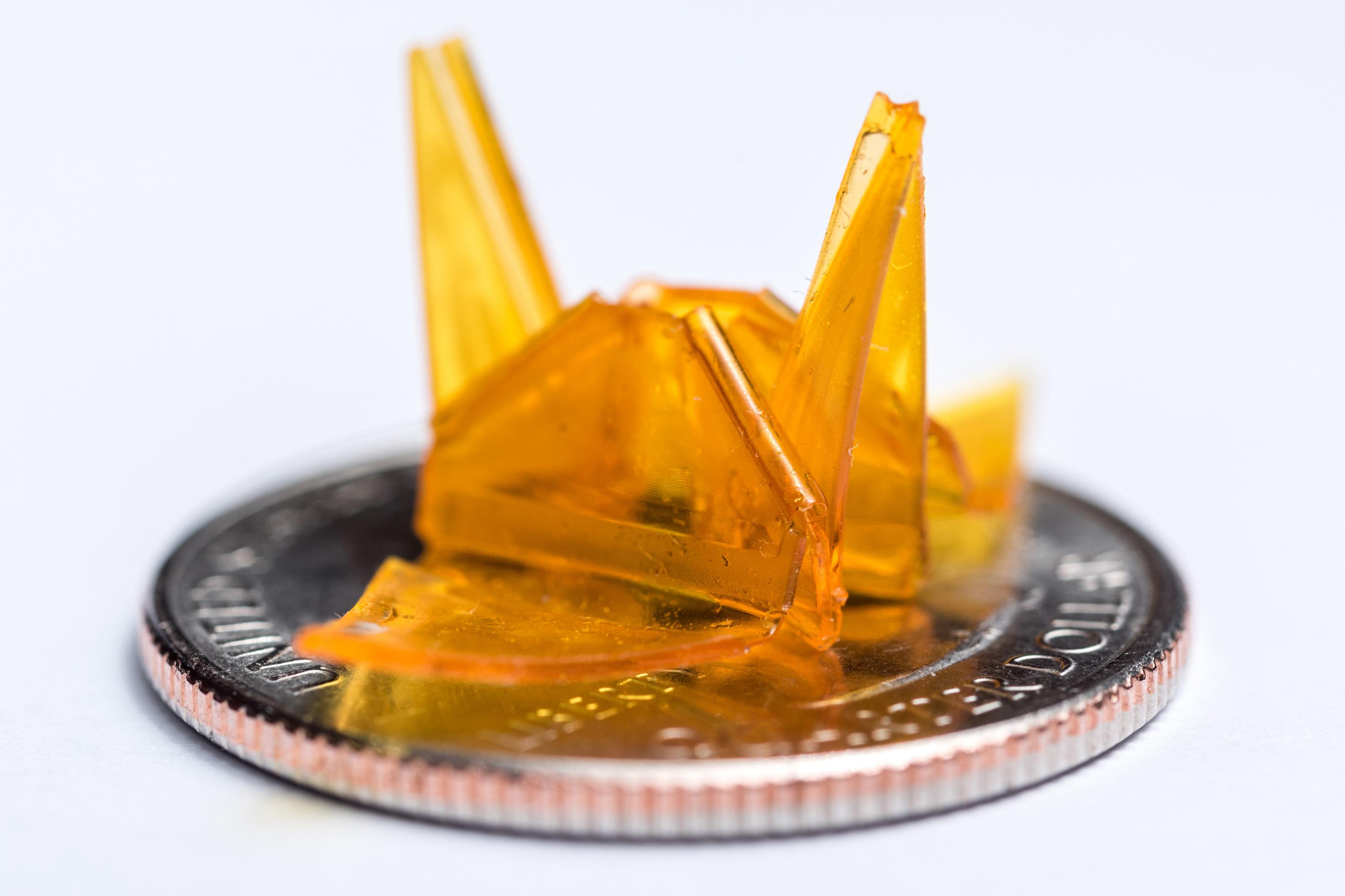 A tiny origami structure created through a self-folding process is shown on a quarter for size comparison. (Credit: Rob Felt, Georgia Tech)