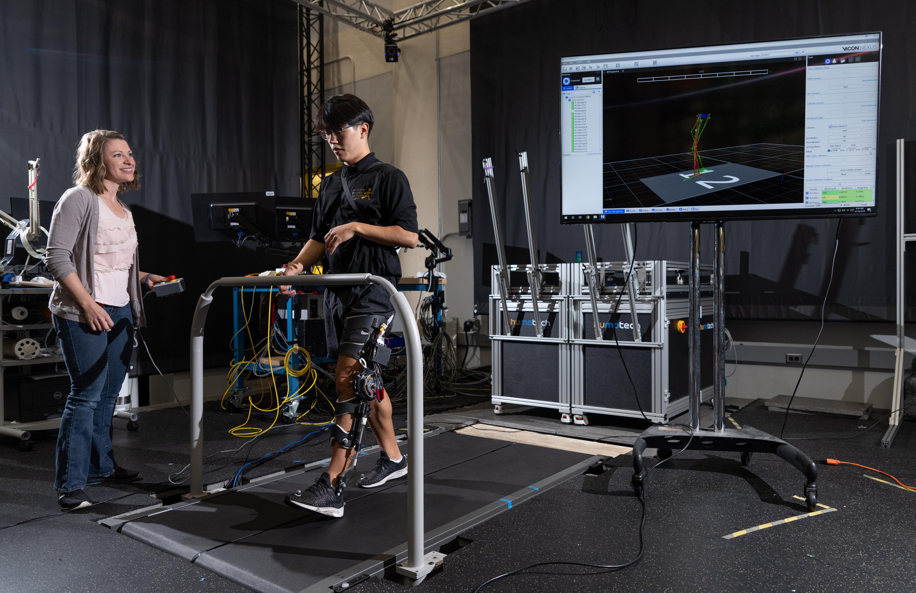 Kinsey Herrin, research scientist in Georgia Tech’s Woodruff School of Mechanical Engineering, observes graduate researcher Dawit Lee as he tests the pediatric knee exoskeleton. (Credit: Rob Felt, Georgia Tech)