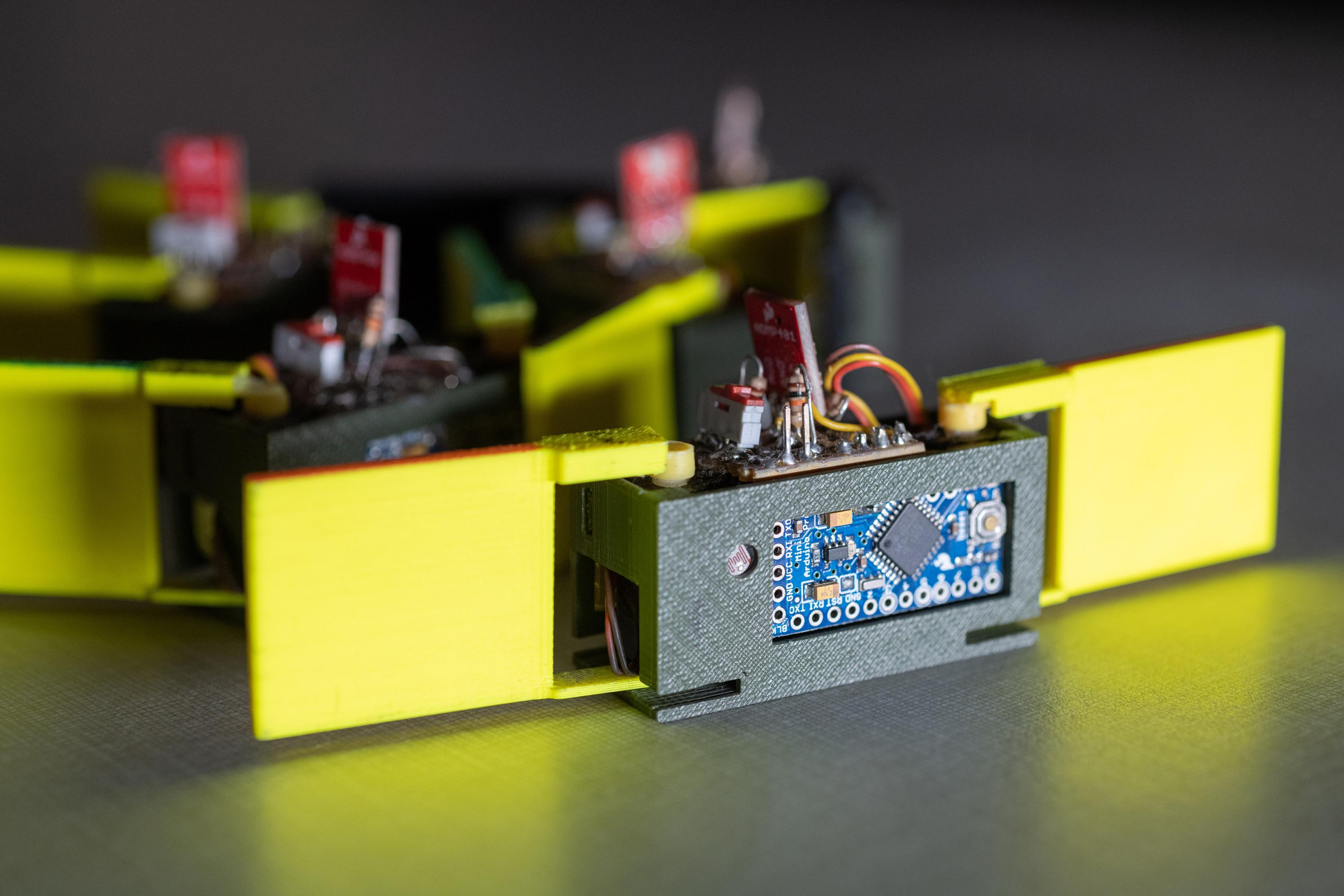 Close-up of a smarticle – smart active particle – showing the two 3D-printed arms, light sensor, and motor. (Georgia Tech Photo: Rob Felt)