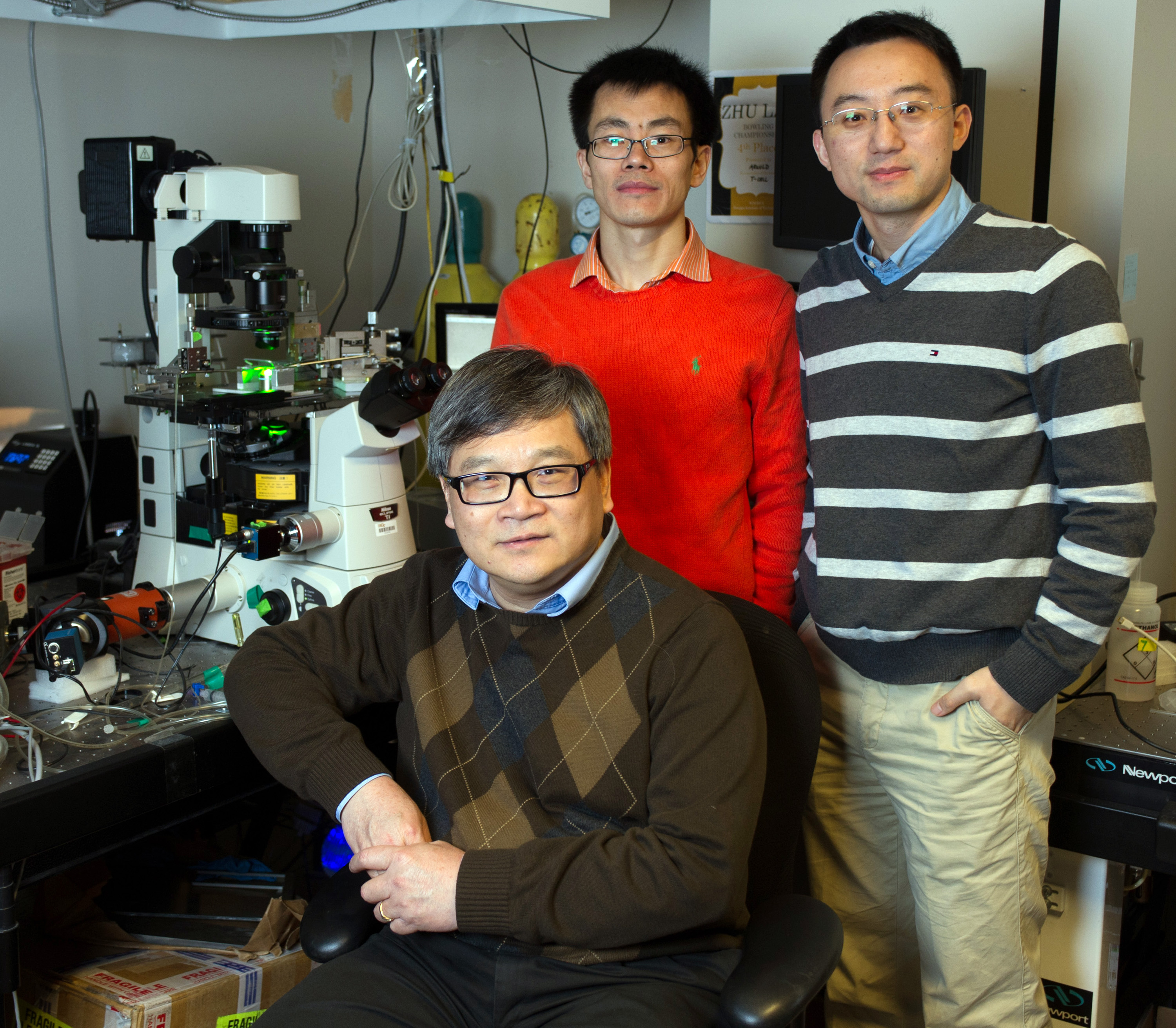 Researchers are shown with biomembrane force probe equipment. They are (l-r) Cheng Zhu (seated), Baoyu Liu and Wei Chen. (Georgia Tech Photo: Rob Felt)