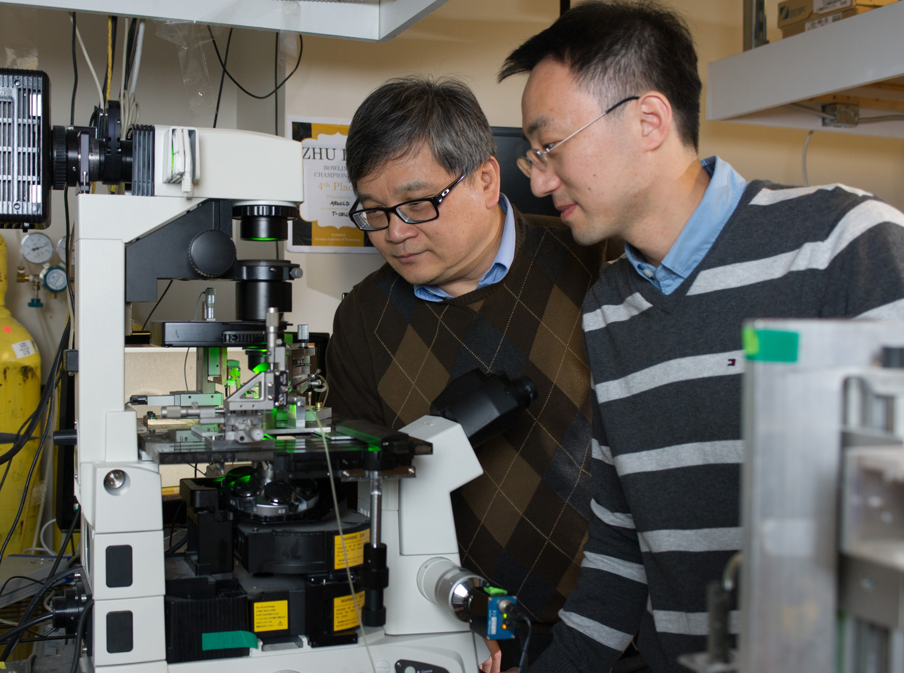 Researchers (l-r) Cheng Zhu and Wei Chen observe a biomembrane force probe experiment. (Georgia Tech Photo: Rob Felt)