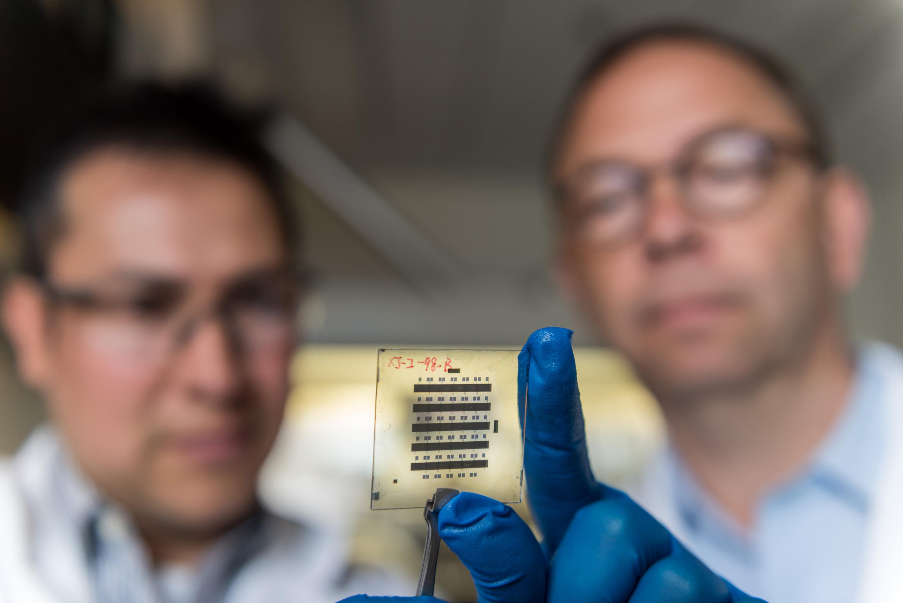 Georgia Tech Senior Research Scientist Canek Fuentes-Hernandez (left) and Professor Bernard Kippelen examine a sample of organic thin-film transistors created with a new nanostructured gate dielectric that gives the devices unprecedented stability. (Credit: Rob Felt, Georgia Tech)