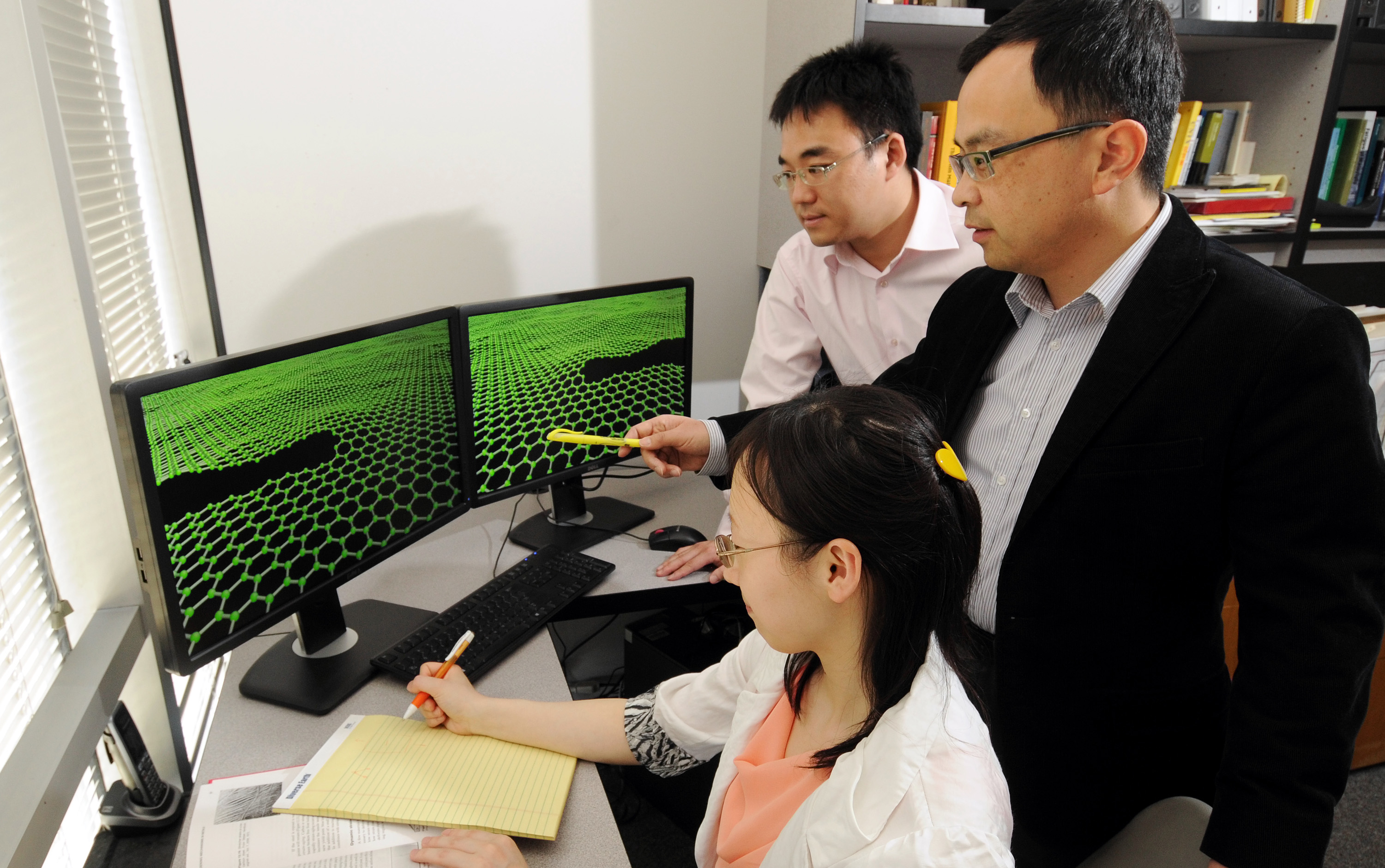 Ting Zhu, right, an associate professor in the George W. Woodruff School of Mechanical Engineering at Georgia Tech, works with graduate students Feifei Fan, seated, and Zhi Zeng to calculate the fracture toughness of graphene that has been pre-cracked. Georgia Tech's calculations and physical experiments at Rice University led to the conclusion that graphene, the one-atom layer of carbon, is only as strong as its weakest link. (Georgia Tech Photo: Gary Meek)