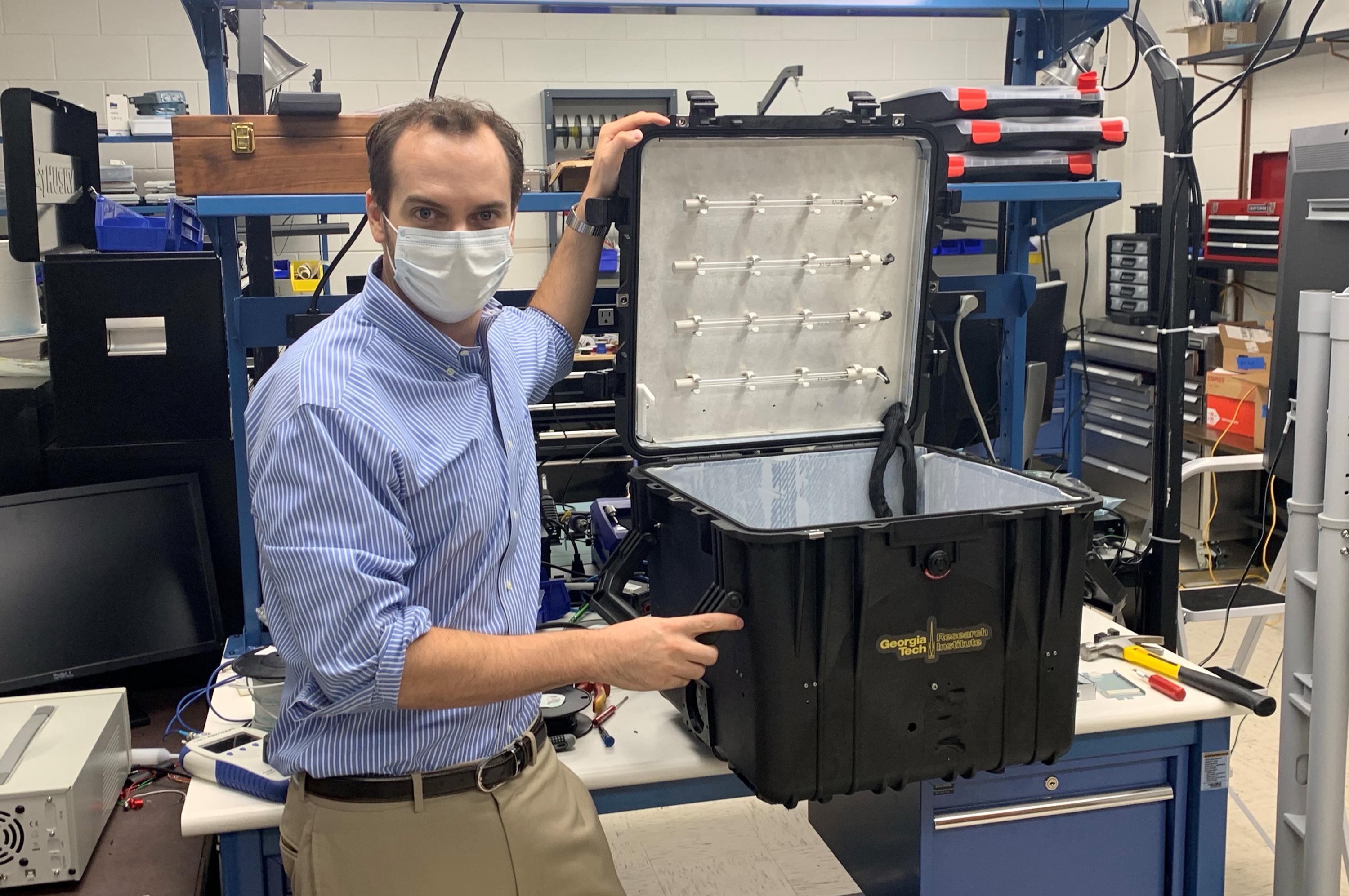 GTRI researcher Robert Harris shows the prototype portable UV disinfection chamber, which was designed to hold at least one face shield along with face masks. (Credit: John Stone)