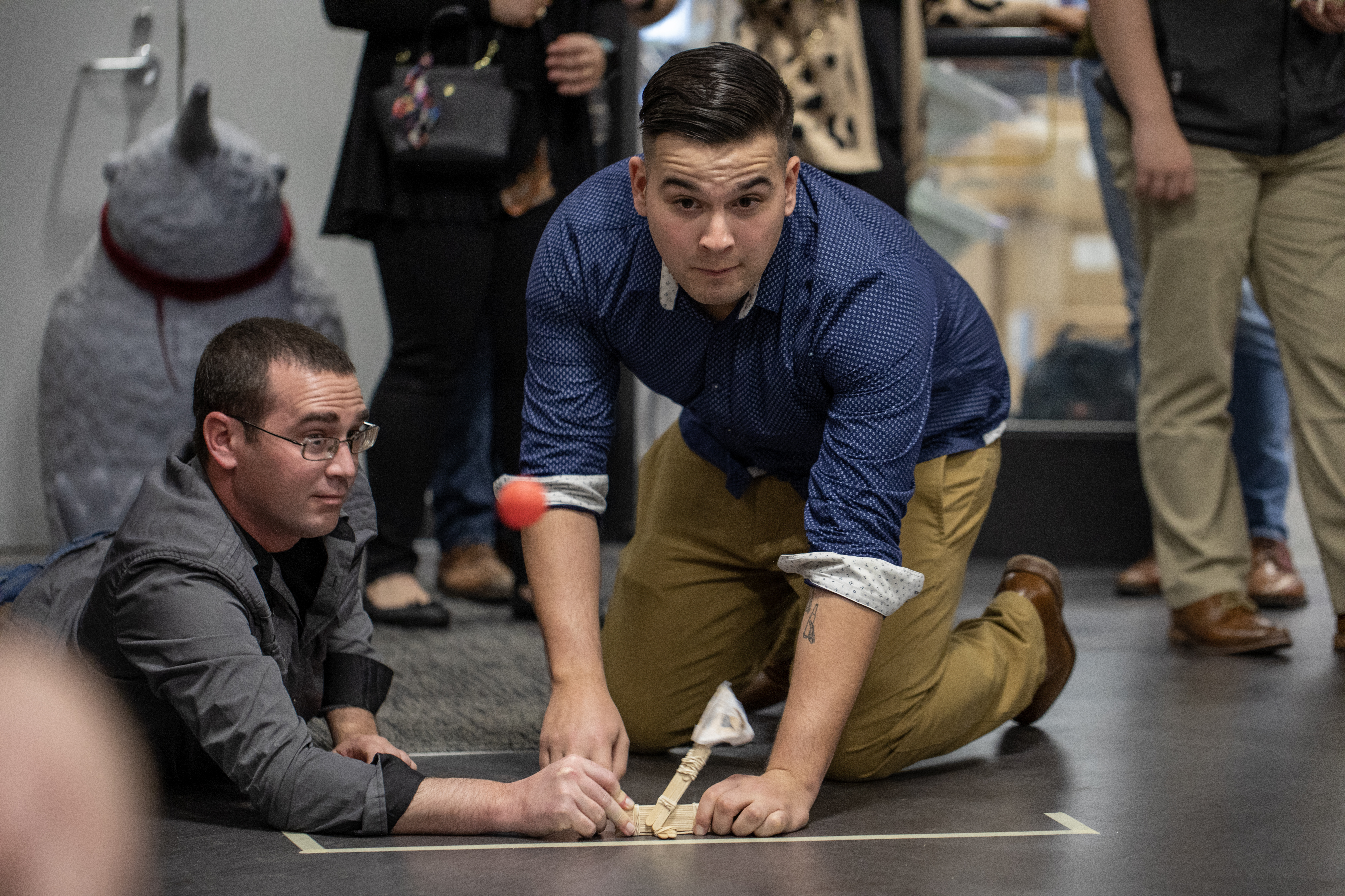 Team members test a catapult made of popsicle sticks, dowels, and rubber bands. 