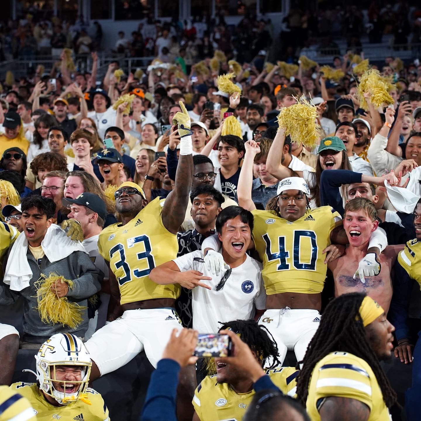 Georgia Tech football players join fans in the stands to celebrate the victory.