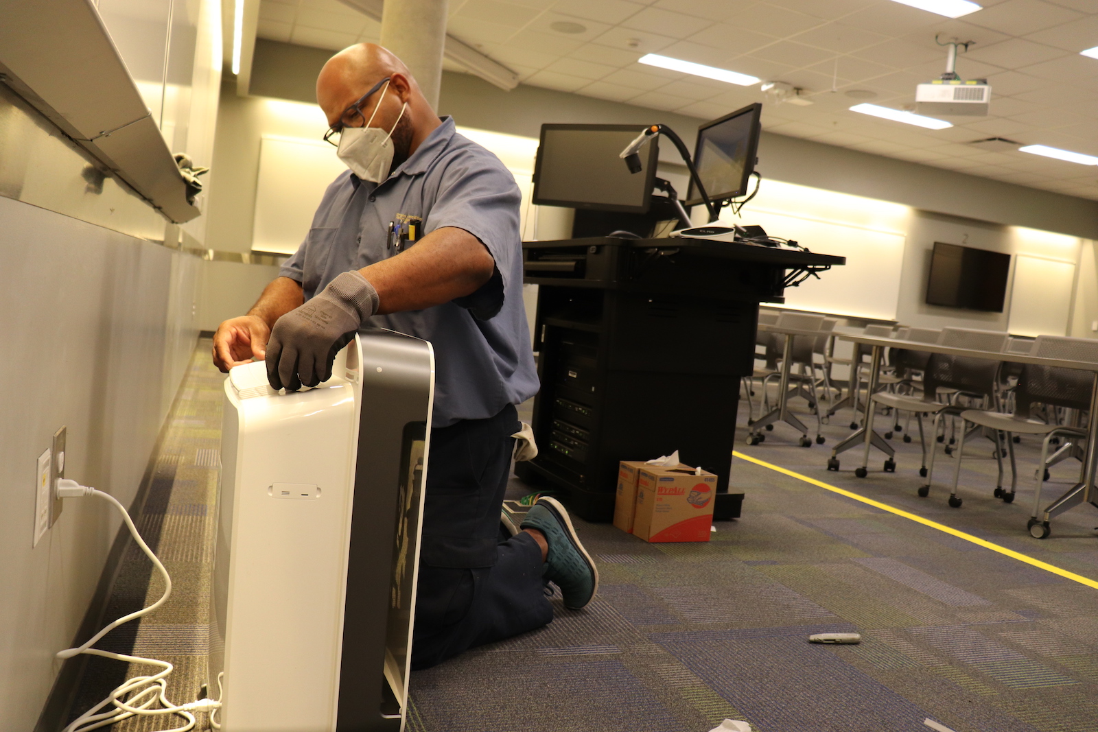 Gerry Green, maintenance worker, installs a portable air purifier in a classroom.