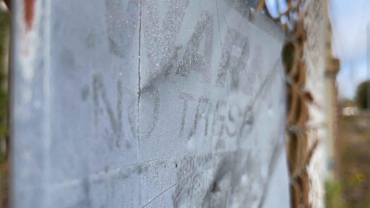 A faded "No Trespassing" hangs on the locked fence of the now closed factory on Dromedary Street.