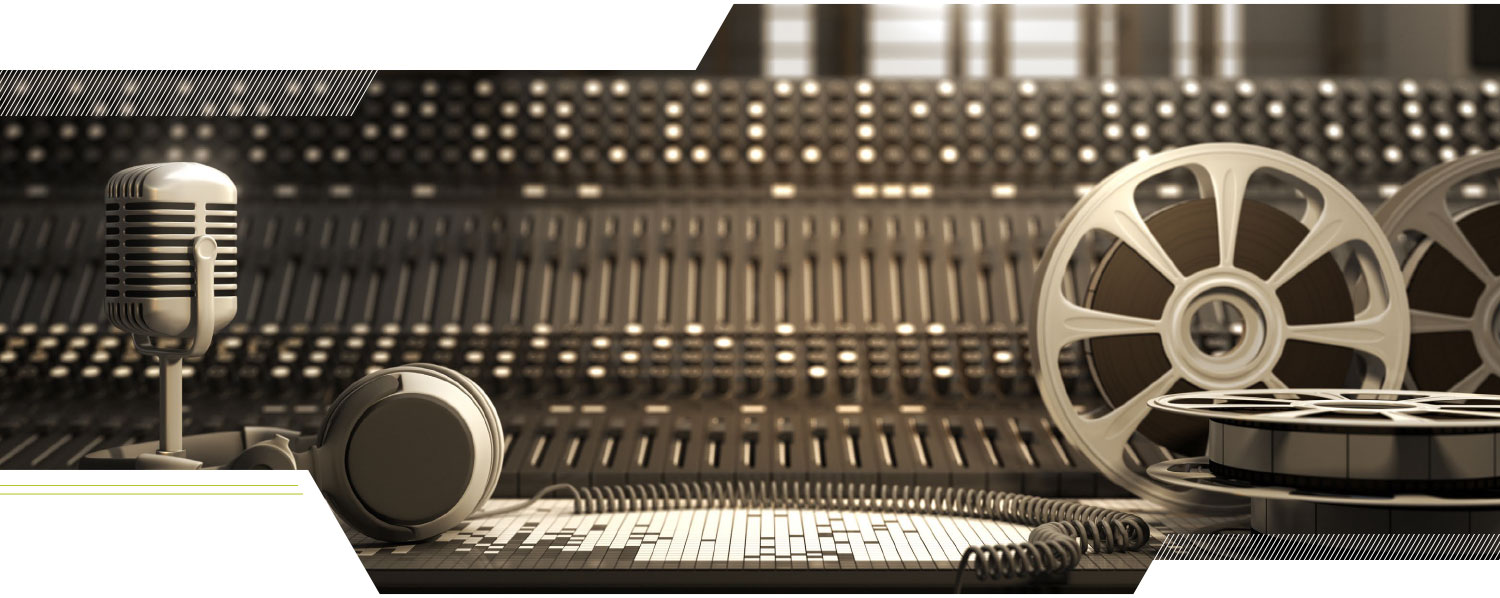 A microphone and film reels sitting in front of a sound mixing board