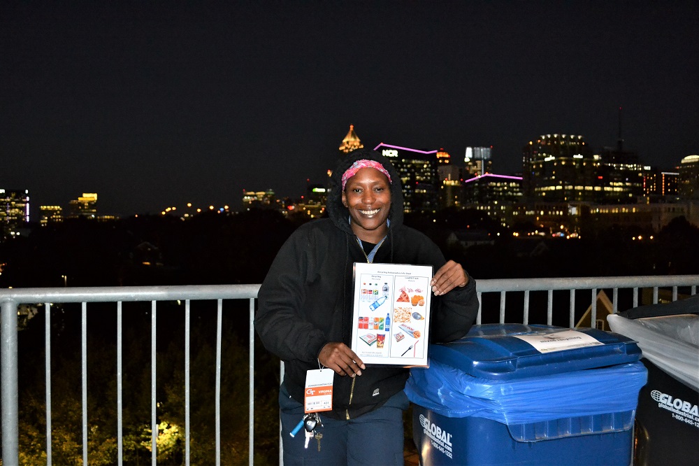 woman holding a brochure by a recycling bin