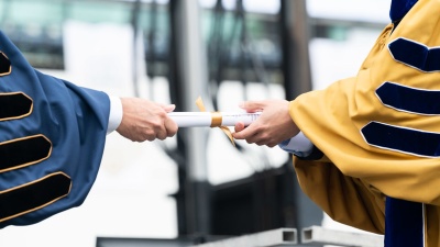 Georgia Tech president hands a ceremonial degree scroll to a new graduate.