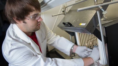 Georgia Tech researcher Andrew Brown places a finished hollow fiber metal-organic framework (MOF) membrane module into a membrane testing apparatus to measure its gas separation properties. (Credit: Rob Felt)