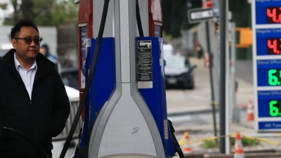 A person filling gas in his car with the gas prices shown in the foreground