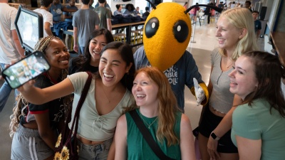 students taking a photo selfie with mascot Buzz.