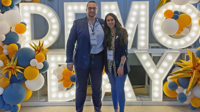 Politheon co-founders Daniel Forcade and Hannah Bodnar stand in front of a lighted sign reading "Demo Day" at the CREATE-X Demo Day in August 2025.