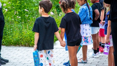 preschool-aged children hold hands and observe as they learn about composting.