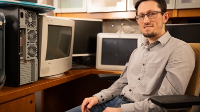 Zsolt Kira sitting in office chair surrounded by old computers