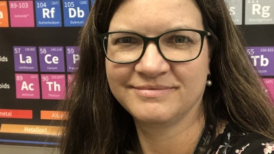 Headshot of a woman in front of a periodic table