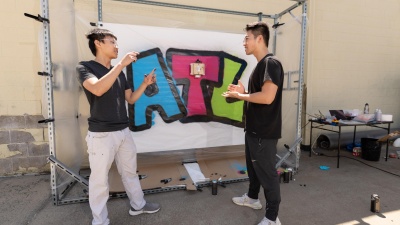 Gerry Chen, Ph.D. candidate in Robotics, and Michael Qian, B.S. Computer Science, '22, with a finished artwork painted by the GTGraffiti robot.