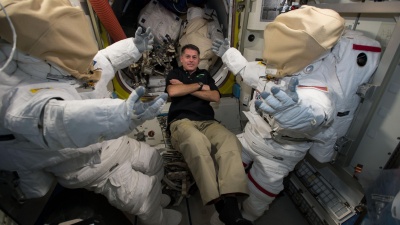 NASA astronaut Shane Kimbrough floats next to two U.S. spacesuits inside the Quest Airlock aboard the International Space Station.