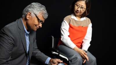 Sundaresan Jayaraman (left) looks at pressure data from fabric sensors he developed with Sungmee Park, who is seated in their prototype wheelchair system. (Photo: Candler Hobbs)