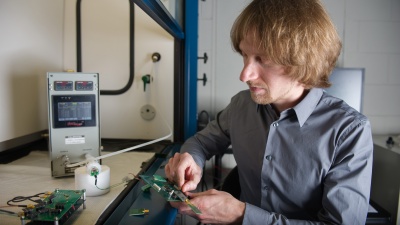 Georgia Tech Research Institute researcher Christopher Valenta inspects the RFID Enabled Sensing Testbed (R.E.S.T.), which allows rapid prototyping of RFID-enabled sensors and RF technology. (Georgia Tech Photo: Rob Felt)