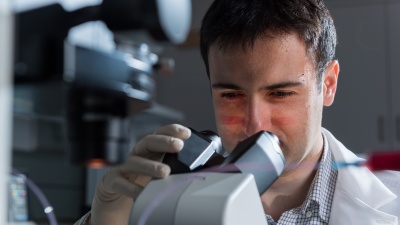 Fatih Sarioglu, an assistant professor in the Georgia Tech School of Electrical and Computer Engineering, is shown examining a microfluidic device designed to capture cancer cell clusters. (Credit: Rob Felt)