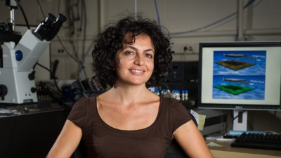 Georgia Tech School of Physics associate professor Elisa Riedo poses with instrumentation used to study how the properties of confining materials affect the effective viscosity of water at nanometer size scales. (Georgia Tech Photo: Rob Felt)
