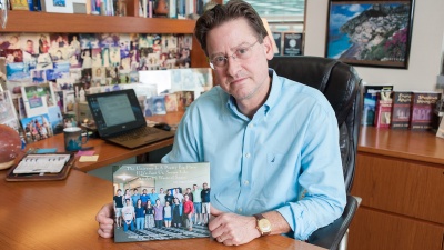 The School of Electrical and Computer Engineering's John Cressler holds a photo of his class from the course Science, Engineering and Religion: An Interfaith Dialogue.
