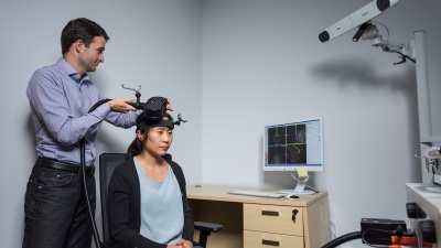 Researcher Dobromir Rahnev demonstrates the application of transcranial magnetic stimulation (TMS) in a Georgia Tech psychology research center with graduate student Ji-Won Jung. Credit: Georgia Tech / Rob Felt
