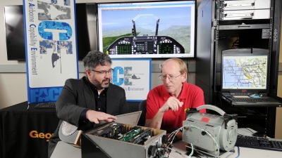 Douglas Woods, left, a research scientist leading the Future Airborne Capability Environment (FACE) project for the Georgia Tech Research Institute (GTRI), discusses the technology with research-team member George Riley, a professor in the School of Electrical and Computer Engineering. (Georgia Tech Photo: Gary Meek)