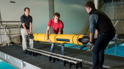 GTRI principal research engineer Mick West, graduate student Jacob Buffo of the School of Earth and Atmospheric Sciences, and undergraduate Matthew Meister of the School of Mechanical Engineering handle the 210-pound Icefin at Georgia Tech’s Underwater Acoustics Research Laboratory.