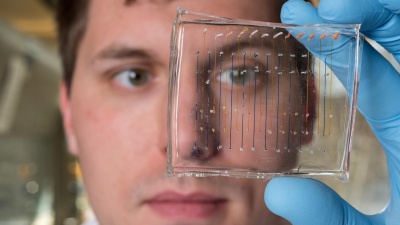 James Dahlman, an assistant professor in the Wallace H. Coulter Department of Biomedical Engineering at Georgia Tech and Emory University, holds a microfluidic chip used to fabricate nanoparticles that could be used to deliver therapeutic genes. (Credit: Rob Felt, Georgia Tech)